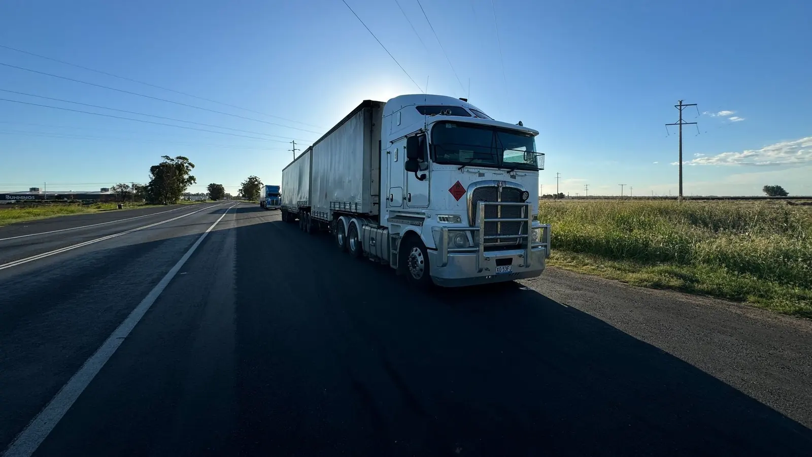 Camión con semirremolque en una ruta abierta a contraluz